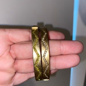 Gold bangles with green and gray gems.